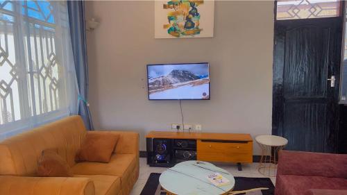 a living room with a couch and a tv on the wall at Otoria Apartments Home away from Home in Dar es Salaam