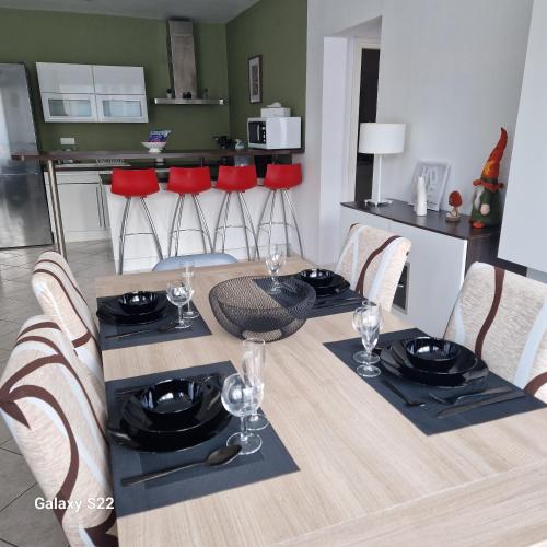 a dining room table with red chairs and a kitchen at Spacieux T3 lumineux avec balneo à 5min de la gare in Épinal