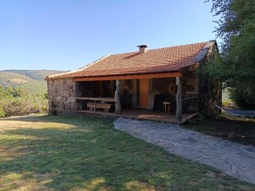 a small stone house with a roof on a field at Casa tapada da branda in Monção