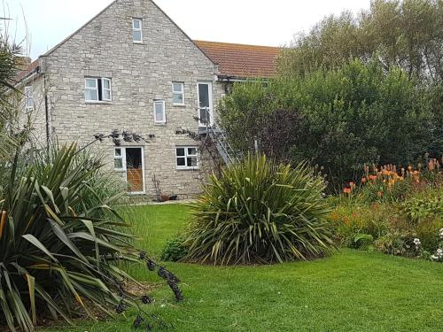 韦茅斯Jurassic Loft Apartment的一座古老的石头房子,前面设有一个花园