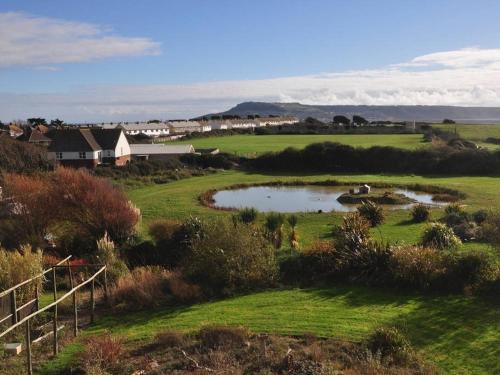 a small pond in the middle of a green field at Jurassic Apartments in Weymouth