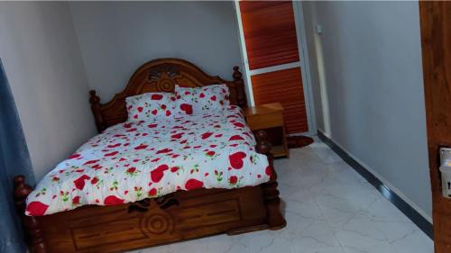 a bedroom with a bed with red flowers on it at Otoria Apartments Home away from Home in Dar es Salaam