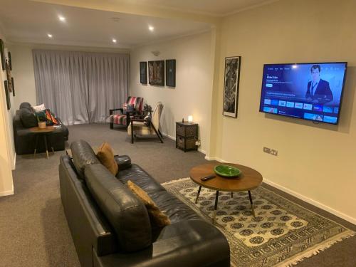a living room with a leather couch and a flat screen tv at Incredible mountain & sea views in Mapua