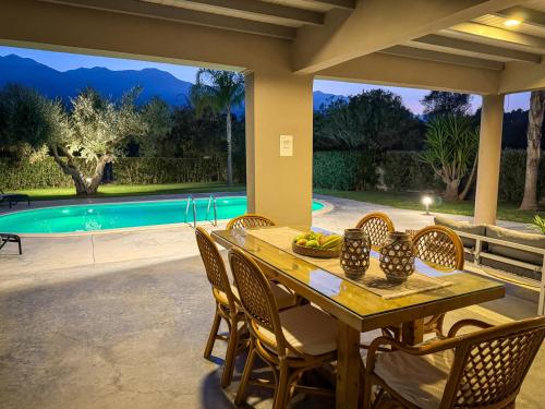 a table and chairs on a patio with a pool at Villa Felenia in Vryses