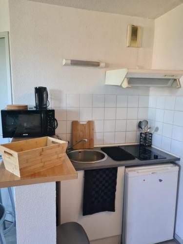 une petite cuisine avec un évier et une cuisinière dans l'établissement Le Zénith, à Sotteville-lès-Rouen