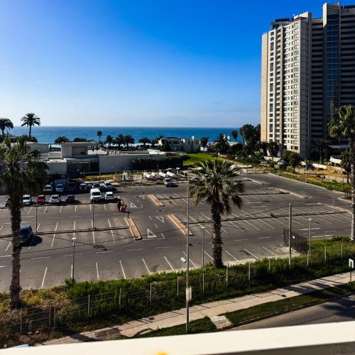 a parking lot with palm trees and a tall building at Departamento Av Los Pescadores in Coquimbo