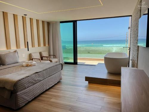 a bedroom with a large bed and a tub and the ocean at Marino Beach Hotel in Cabo Frio