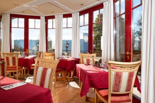 a restaurant with red tables and chairs and windows at Sonnhof am Hochkönig in Mühlbach am Hochkönig
