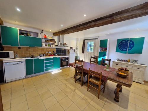 une cuisine avec des placards verts et une table avec des chaises dans l'établissement Charmante Maison campagne Tarn, à Loupiac