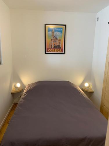 - un lit dans une chambre avec une photo sur le mur dans l'établissement Les apparts de St Jo, à Ajaccio
