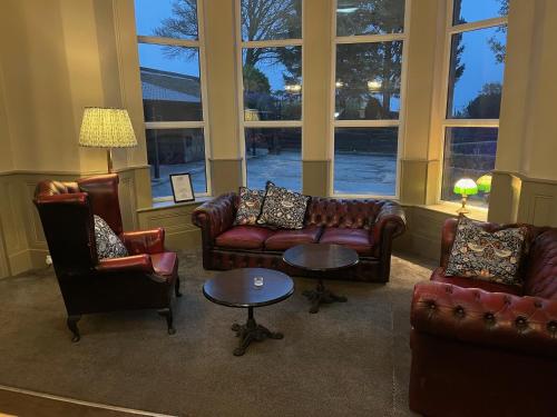 a living room with couches and tables and windows at Whiston Hall in Whiston