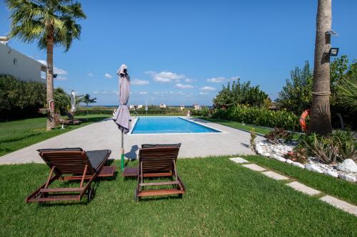 two chairs and an umbrella next to a swimming pool at Socrates Holidays Apt. 2 with Pool near the Beach in Plataniás