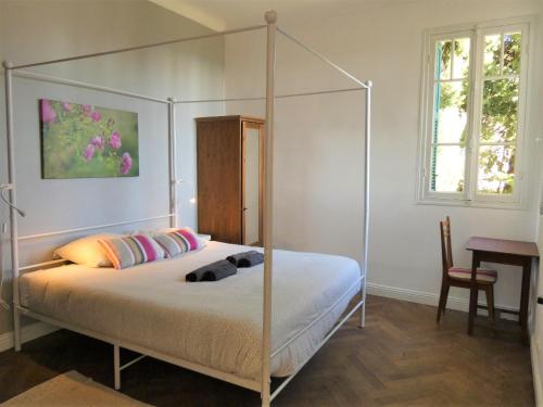 - une chambre avec un lit à baldaquin, un bureau et une fenêtre dans l'établissement Mas Saint Jeaume 10 personnes piscine, à Châteauneuf