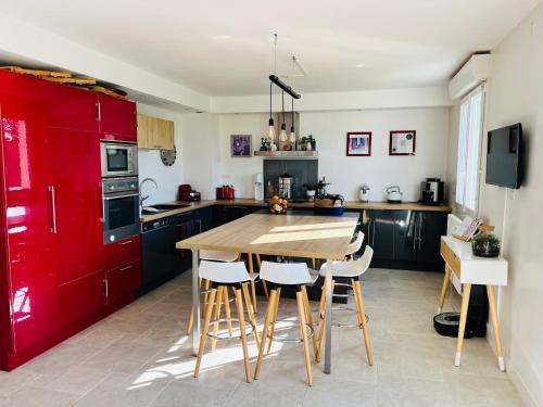 une cuisine avec une table en bois et des placards rouges dans l'établissement Maison dans cadre verdoyant, 20min des plages, à Bréhand