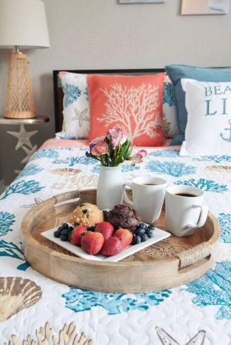 a tray of fruit on a bed with two cups at Serenity by the Sea Heated Pool and Spa in Apollo Beach