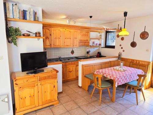 a kitchen with wooden cabinets and a table with a television at Fior di Larice - Alpine Stay Apartments in Ziano di Fiemme