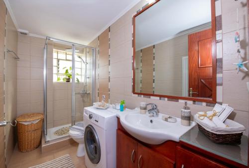 a bathroom with a sink and a washing machine at Socrates Holidays Apt. 2 with Pool near the Beach in Plataniás
