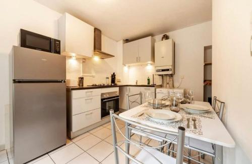 une cuisine avec une table avec des chaises et un réfrigérateur dans l'établissement Belle Chambre chez l'habitant frontière Luxembourg, à Audun-le-Tiche