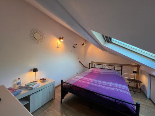 - une chambre mansardée avec un lit et un bureau dans l'établissement Belle Chambre chez l'habitant frontière Luxembourg, à Audun-le-Tiche