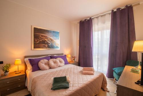 a bedroom with a bed with purple pillows and a window at Sopra le nuvole Casa Vacanza FCO in Fiumicino Airport