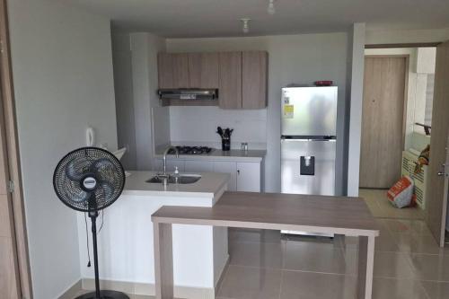 a kitchen with a refrigerator and a table with a fan at Arriendo Apto Peña Azul La Aldea in Ricaurte