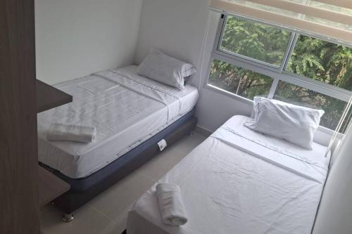 two beds in a small room with a window at Arriendo Apto Peña Azul La Aldea in Ricaurte