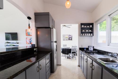a kitchen with black counter tops and a refrigerator at Mango y Jobo - Relaxed Mountain & Sea Panoramic view - 10mins drive to beach and city in San Felipe de Puerto Plata