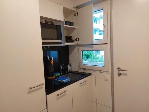 a kitchen with white cabinets and a sink and a window at El Destino Apartments in Zürich