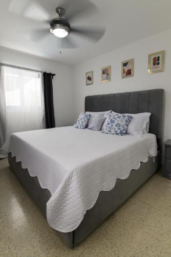 a bedroom with a large bed with white sheets and blue pillows at Mango y Jobo - Relaxed Mountain & Sea Panoramic view - 10mins drive to beach and city in San Felipe de Puerto Plata