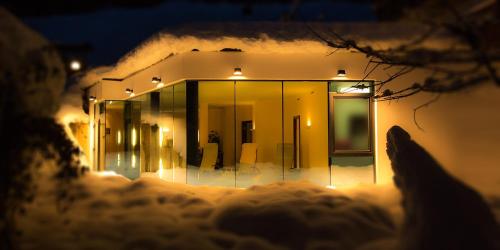 a building with lights in the snow at night at Hotel Vista Carnica in Kartitsch