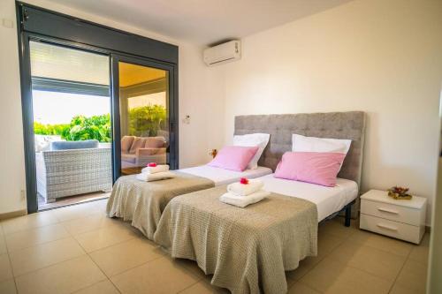 a bedroom with two beds with pink pillows and a balcony at Kisara, Villa moderne 6 pers Piscine in Saint-François