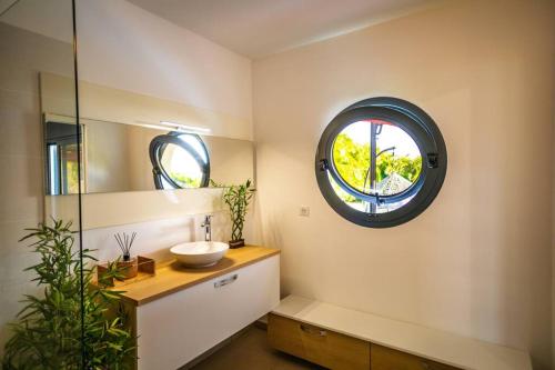 a bathroom with a sink and a round window at Kisara, Villa moderne 6 pers Piscine in Saint-François