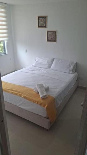 a white bed in a white room with towels on it at Arriendo Apto Peña Azul La Aldea in Ricaurte