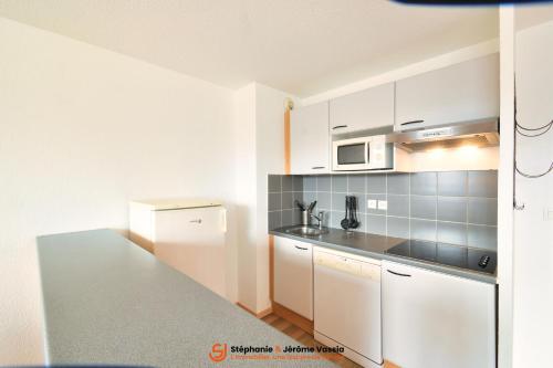 a kitchen with white cabinets and a counter top at Résidence Les Adrets de Peyragudes in Germ