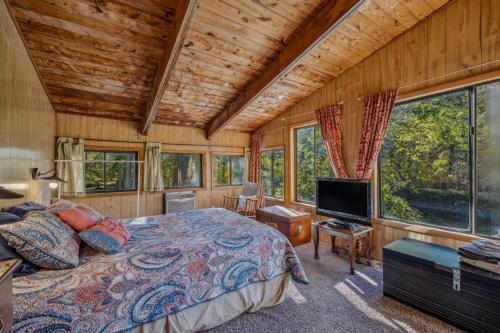 a bedroom with a bed and a flat screen tv at River Song Retreat - Right on the River! in Great Cacapon