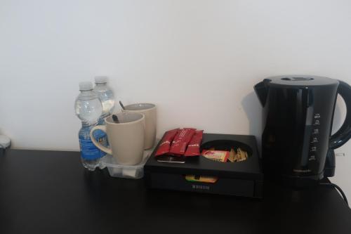 a counter top with a coffee maker and a coffee pot at cozy room in Kent