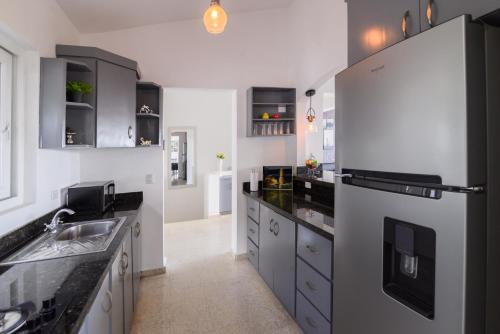a kitchen with a refrigerator and a sink at Mango y Jobo - Relaxed Mountain & Sea Panoramic view - 10mins drive to beach and city in San Felipe de Puerto Plata
