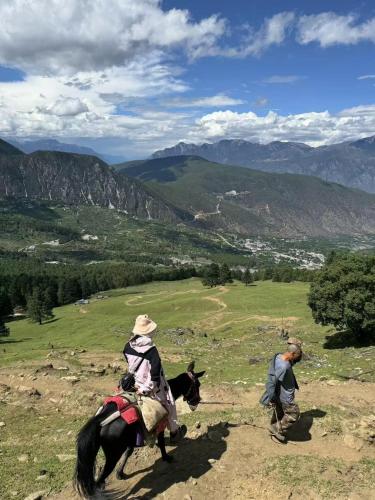 a couple of people riding a horse on a hill at Gucheng Lanshe Designer Garden B&B in Lijiang