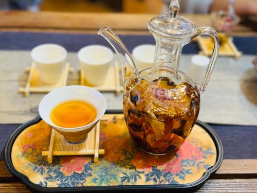 a glass jug of tea on a plate with a cup at Gucheng Lanshe Designer Garden B&B in Lijiang