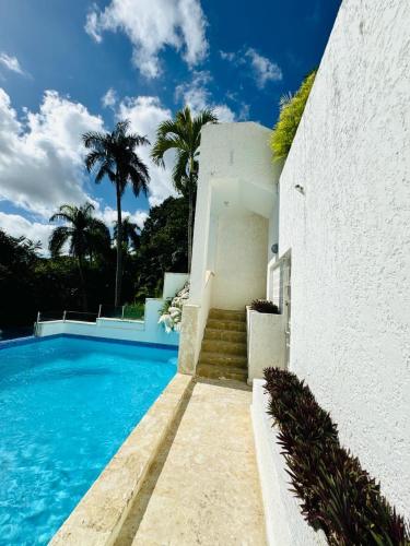 a house with a swimming pool and palm trees at Mango y Jobo - Relaxed Mountain & Sea Panoramic view - 10mins drive to beach and city in San Felipe de Puerto Plata