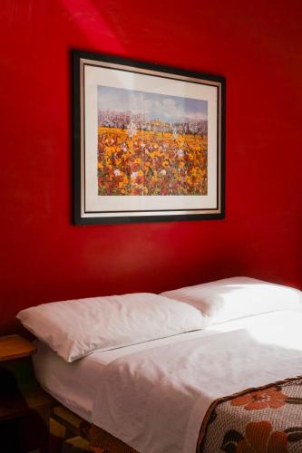 a red wall with a picture above a bed at La Casa Zen in San Giovanni Teatino