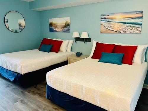 two beds in a room with blue walls and red pillows at Endless Ocean View Beachfront 1131 in Myrtle Beach