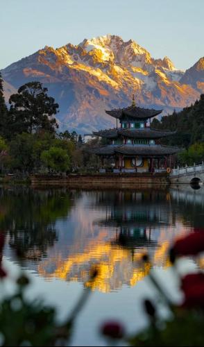 a building on the water with a mountain in the background at Gucheng Lanshe Designer Garden B&B in Lijiang