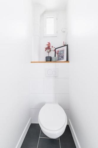 La salle de bains est pourvue de toilettes blanches et d'une étagère. dans l'établissement Super Apt Tolbiac-buttes Cailles, à Paris