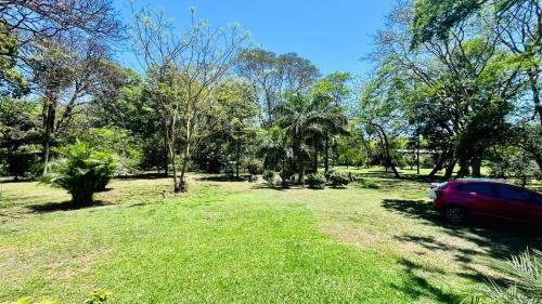 a red car parked in a field with trees at Amplia y hermosa casa quinta de 4 habitaciones in Asuncion