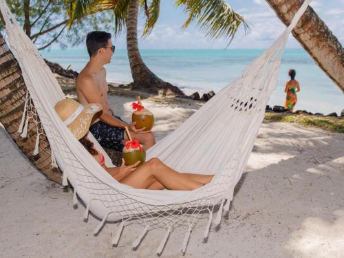 a man sitting in a hammock on a beach at La VILLA BORAHA 300m2 PROPRIÉTÉ ENTIERE en bord de plage PISCINE PRIVEE Cuisine TV Wifi in Sainte Marie