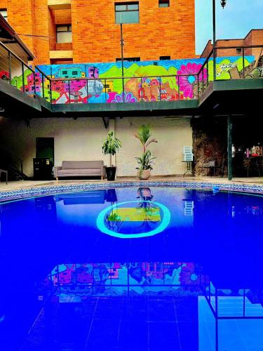 a large blue swimming pool with a fountain in front of a building at Casa Boutique La Corona Medellin in Envigado