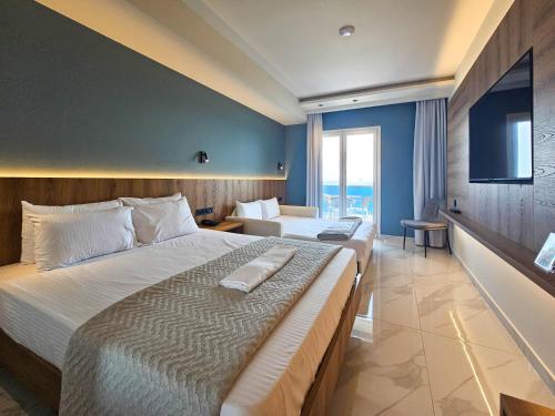 a hotel room with two beds and a television at AKTEON GIRNI in Paralia Katerinis