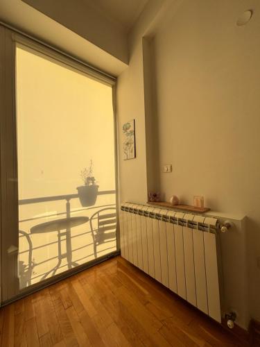a room with a balcony with a table and a glass door at Goca Apartment in Skopje