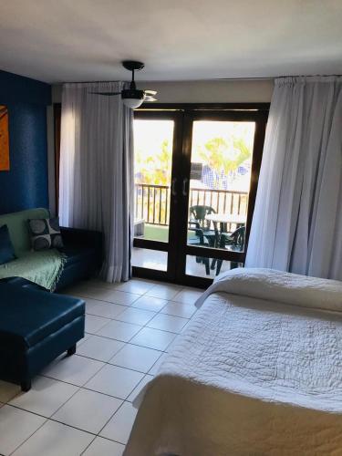 a bedroom with a bed and a couch and a balcony at Flat pé na areia Ponta Negra Natal RN 09 in Natal